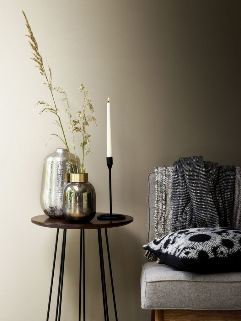 Modern grey sofa with dark wood side table decorated with a selection of vases and black candle holder