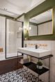 Luxurious bathroom with marble tiles, green wall, large mirror and marble sink