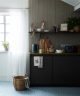 Dark grey kitchen cabinets with light wooden panelling and bright tiled floor.