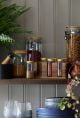 Glass jars with gold lids next to a black pestle and mortar set from Dunelm.