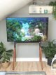 Modern easel TV stand setup with large TV on mid-century style easel stand with wooden legs