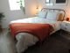 Grey duvet on bed with chunky knit orange throw