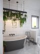 White shiny tiled bathroom with grey roll top bath and beautiful green hanging plants.