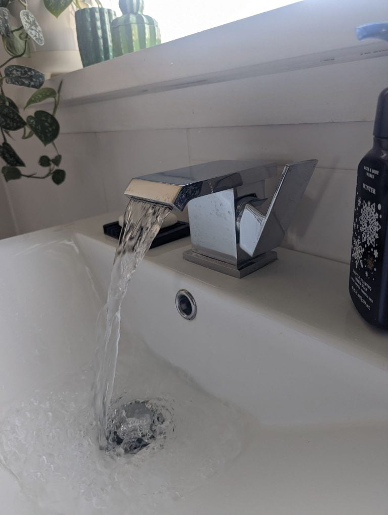 Modern stainless steel waterfall tap with handle to the right.