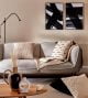 Soft plush grey sofa adorned with waffle cushions, blankets and a black and white art on the wall behind.