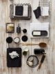 Flatlay of a bobble bath mat, face clothes in a basket, black accessories and soft plush white towels.