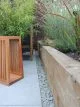 Light grey patio tiles, lined with grey shingles alongside a wooden raised border.