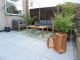Modern patio area with plant print rug, grey sofas and plants.
