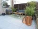 Modern patio area with plant print rug, grey sofas and plants.