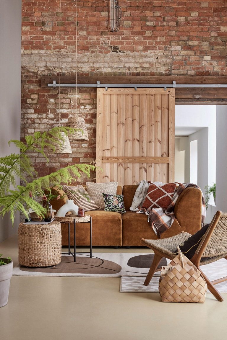 George Home at Asda autumn homeware image with orange berber cushion, natural woven wood basket, nested check print throw and natural rugs.