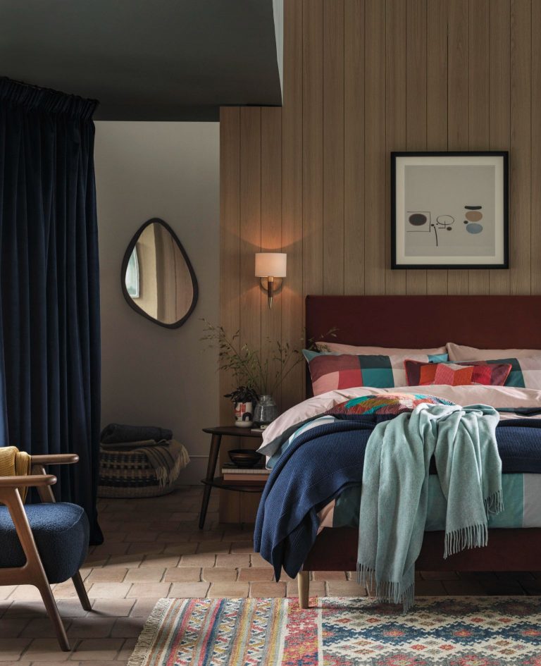 Dark brown bed, wood panelled accent wall and mid-century inspired occasional chair by John Lewis.