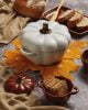 White pumpkin shaped casserole oven dish and dark orange pumpkin ramekins for a thanksgiving dinner table style.