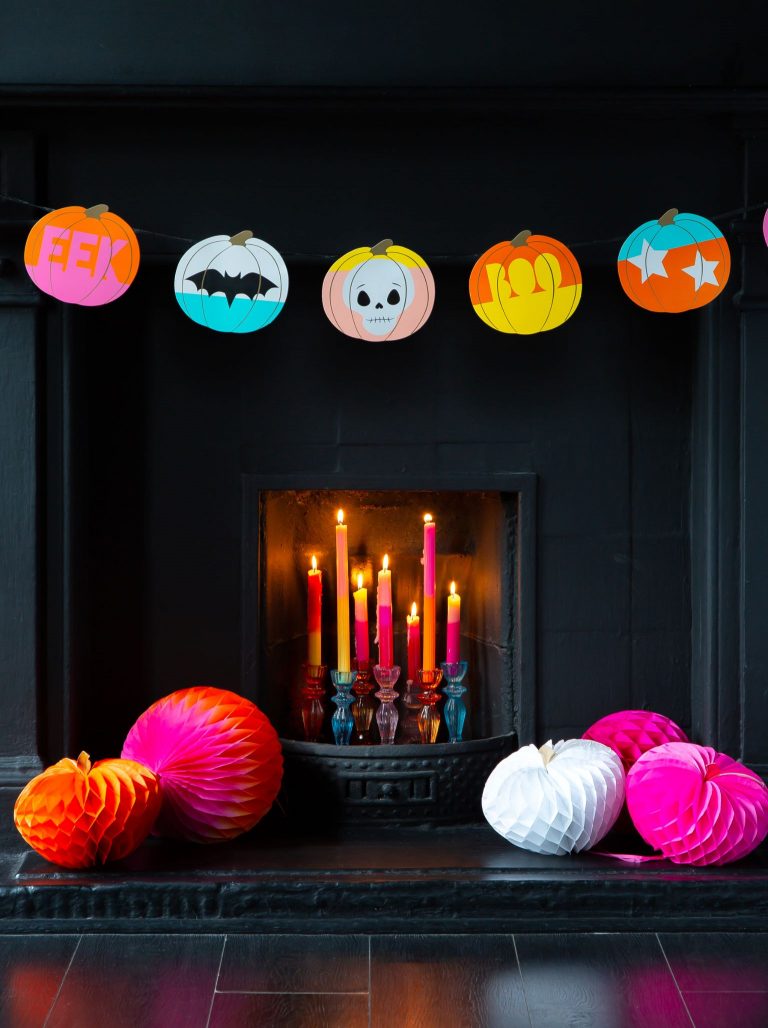 Black fireplace with colourful pumpkin halloween bunting and colourful paper honeycomb pumpkin decorations.