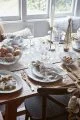 Christmas party dinner table with a white runner, gold snowflake placemats, glass snowflake dishes and Christmas decorations.