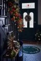 Victorian house entrance hall painted in navy blue with a tiled floor, gold side table and extravagant Christmas decorations.