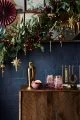 Wooden side table with gold cocktail shaker, cocktail accessories and green garland.