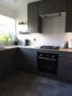 Grey kitchen with white and black zig-zag tiles, black cooker and hob