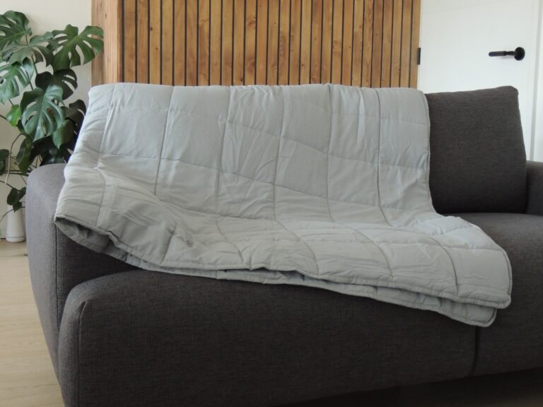 Grey weighted blanket being used on a sofa.