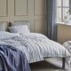 White bedding with grey and blue stripes.