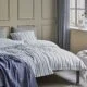 White bedding with grey and blue stripes.