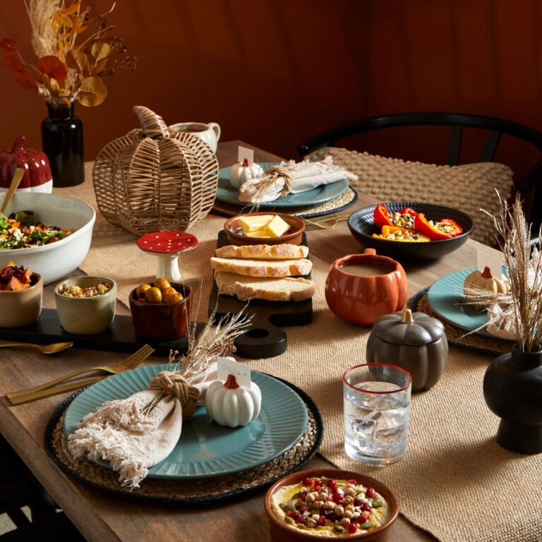Autumn table with pumpkin shaped mugs, small white pumpkin name tag holders and wooden autumn accessories.
