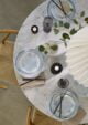 A table set for a meal. There are two plates, two bowls, two sets of chopsticks, and a candle on the table. The plates are blue and white, the bowls are white, and the chopsticks are black and white. The table is white and has a marble top. 