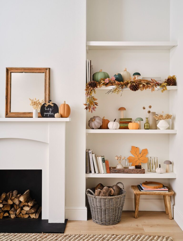 A living room with a fireplace and a bookshelf decorated for fall. The bookshelf is filled with books, pumpkins, and other fall-themed decorations.