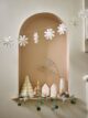 Shelf filled with ceramic Christmas houses, paper Christmas tree, eucalyptus bunting and paper snowflake garland from Garden Trading.