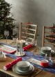 Colourful Christmas dinner table with a Christmas tree table runner, green dinner plates and red crackers from Habitat.