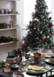 Dark wood dining table with a floral velvet table runner, dotted with plates, cutlery and plum pressed tumblers from Habitat.