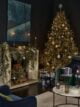 Dark navy lounge with large Christmas tree, fireplace covered in greenery and hanging decorations by Marks and Spencer.
