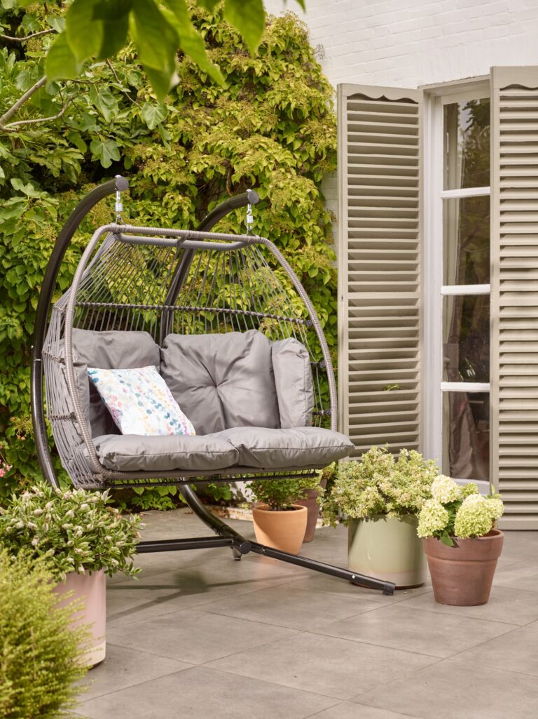 Hanging two-seater outdoor egg chair with grey rattan and cushions by Dobbies.