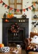 Black fireplace with Halloween bunting, mugs and cushions.