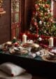 Dark green Christmas dinner table, filled with dinner plates, candles, crackers and cutlery.