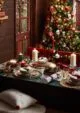 Dark green Christmas dinner table, filled with dinner plates, candles, crackers and cutlery.