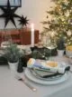 Christmas dinner table with wreath, trees and cocktail Christmas cracker.