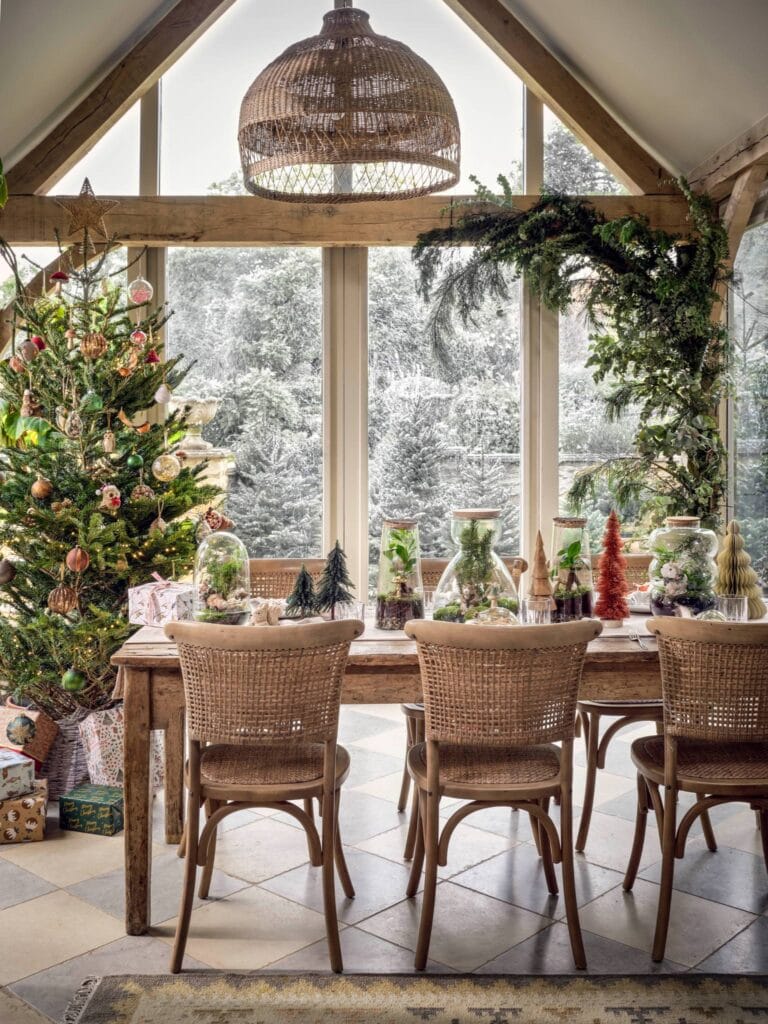 Large, bright and airy Christmas dinner table in a dining room. Festive tree terrariums placed on the table for a stylish look.