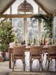 Large, bright and airy Christmas dinner table in a dining room. Festive tree terrariums placed on the table for a stylish look.