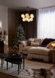 Modern stylish living room with a mantlepiece full of Christmas trees and a garland. In the corner is a slim snowflake topped Christmas tree.