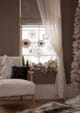 Cosy chair with a white tree shaped cushion, next to a window with a garland and paper snowflakes hanging from the glass. A scandi Christmas look.