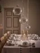 Simple white Christmas dining table with large hanging snowflake baubles.