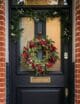 Wow, check out this festive front door! It's got a beautiful wreath with red berries and greenery, and there's even a garland draped across the top. It's the perfect way to welcome guests during the holiday season!